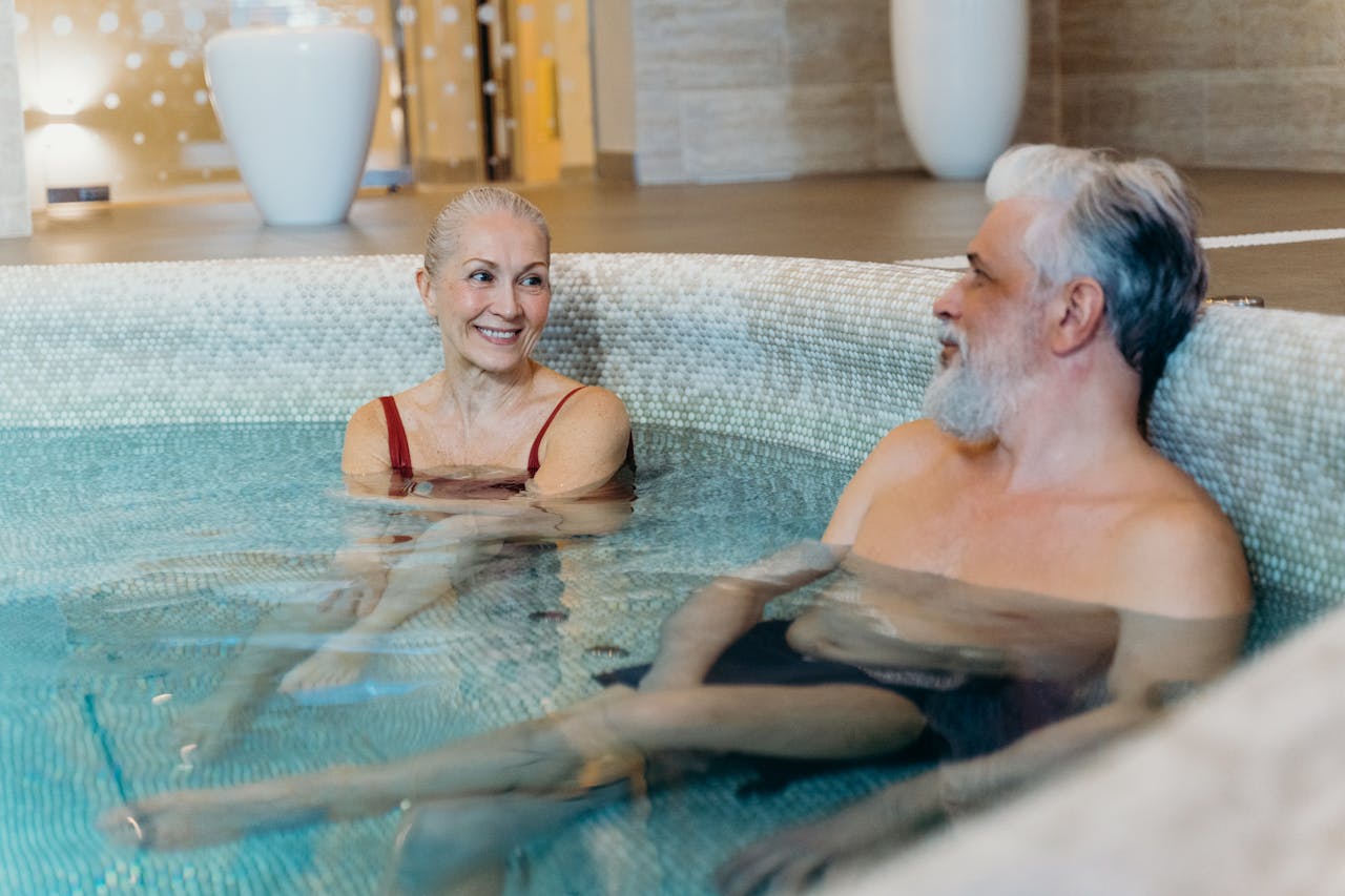 gallery-4 Smiling senior couple relaxing together in an indoor spa pool, enjoying leisure time.